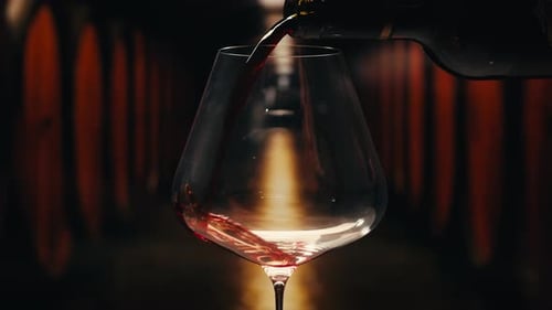 Orange or Red Wine Bottle and Glass Against a Sunset in a Peaceful Vineyard Pouring of Ecological