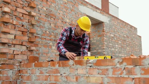 Young Adult Bricklayer Working on Wall Construction
