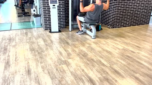 Focused man seated, performing weightlifting exercises with determination in the gym
