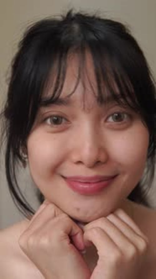 Close up footage of a young Asian woman showing her bare face before applying make up.