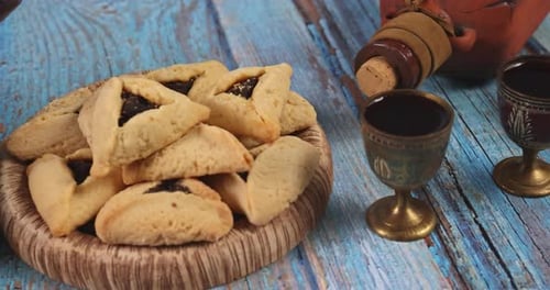 Hamantaschen Cookies and Wine Goblets on Wooden Table