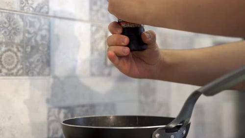 Close up adding seasoning to the dish in the pan 4K