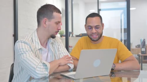 Young Adults Collaborating on Laptop in Bright Office
