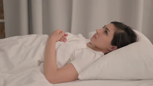 Side View of Brainstorming Young Indian Woman Lying in Bed