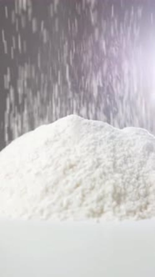 Flour Being Poured Onto a Mound in a Kitchen Setting with Soft Lighting and Blurred Background