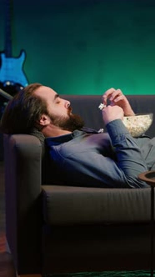 Man Eats Popcorn on Gray Couch