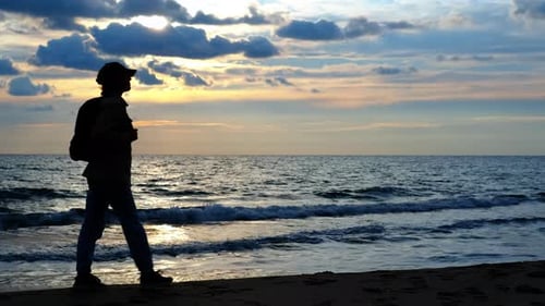 Silhouette eines Mannes, der bei Sonnenuntergang über den Ozean nachdenkt