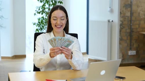 Woman Holding Money at Office Desk