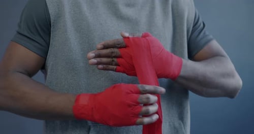 Closeup of African American Boxer Preparing for Fight Wrapping Hands Hitting Fists on Purple Color