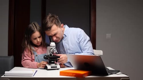 Child and Adult Looking Through a Microscope