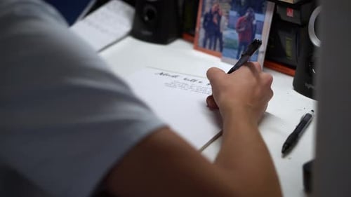 Person Writing in Notebook at Desk Indoors