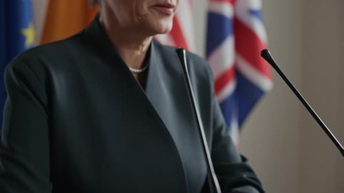 Woman Speaking at a Press Conference With Flags
