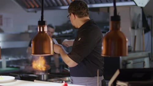 Chef Reading Order Ticket and Taking Notes in Restaurant Kitchen