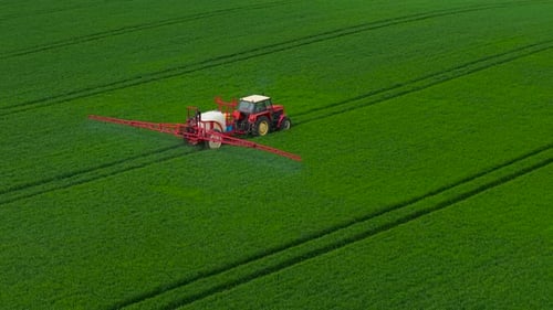 Farming Tractor Spraying on Field with Herbicides Agricultural Machine Treating Crops with Weed