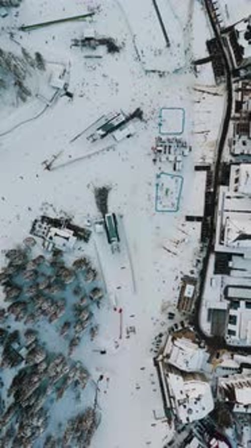 Vertical aerial view of busy ski base area with large crowd waiting for lift