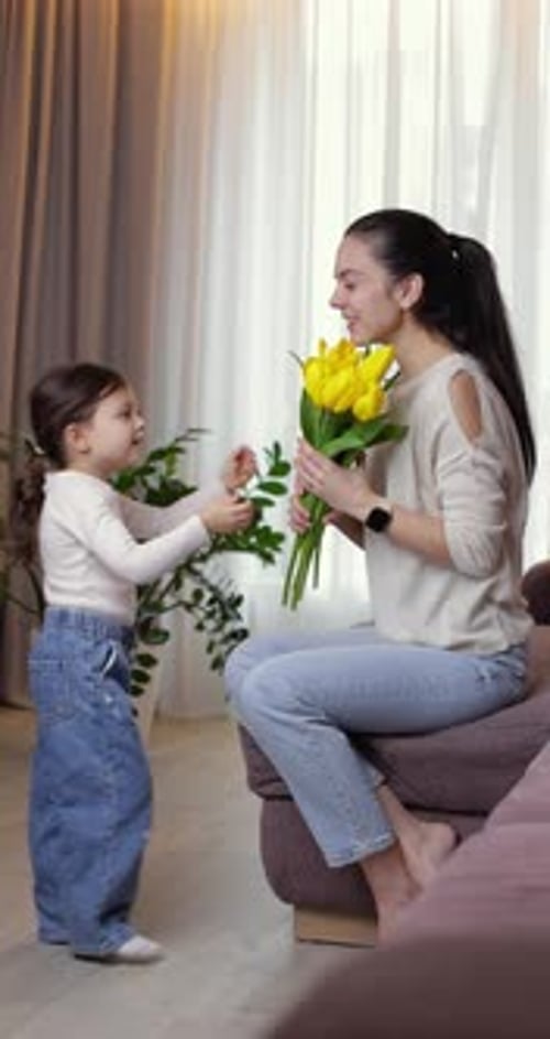 Girl Gives Yellow Flowers to Woman at Home