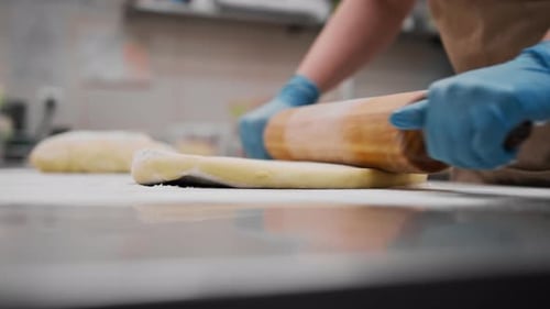 The kitchen in the bakery - the process of preparing cinnabons, the woman baker forms doughs