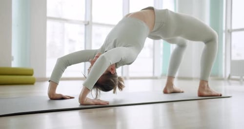 Une belle femme pratique une position de yoga dans le Bright Studio Chakrasana