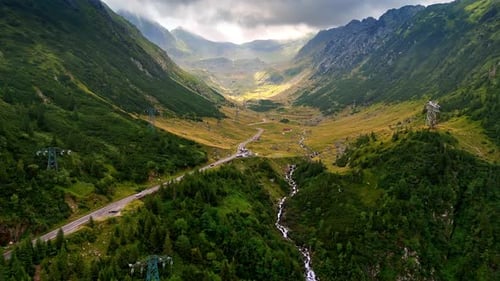 Spectacular green mountains from drone footage. A highway and narrow river pass among the rocks.