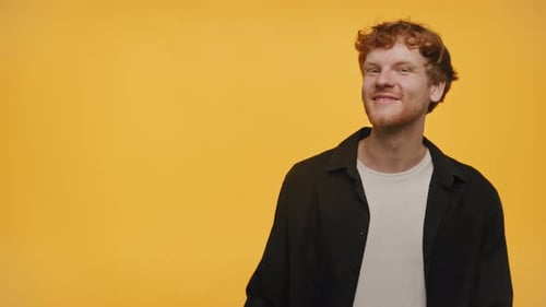 Happy Man Pointing to Side on Yellow Background