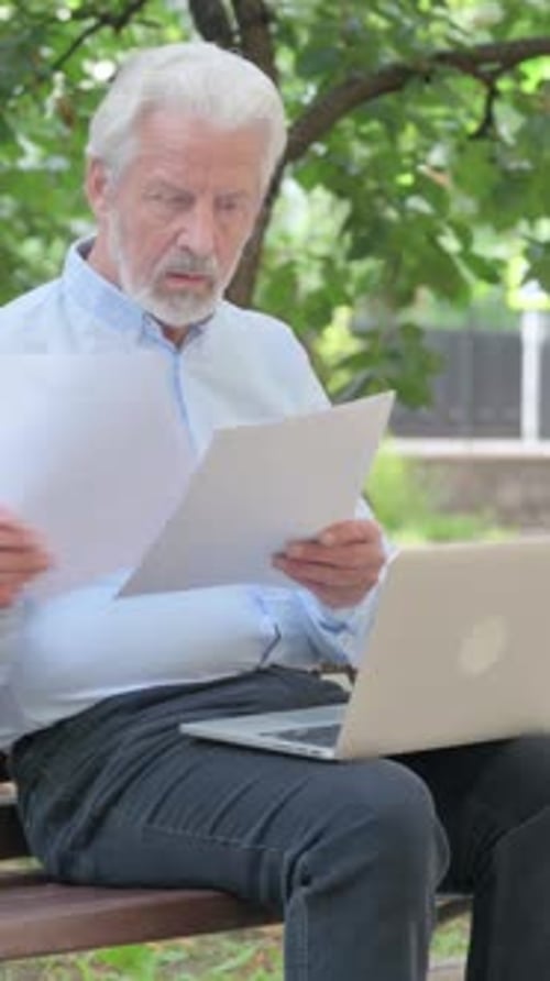Senior Man Reviews Documents on Park Bench