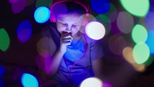Child Uses Tablet with Bokeh Lights in Dark