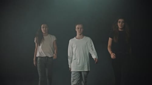 A Group of Three Dancers Walking Out From the Dark
