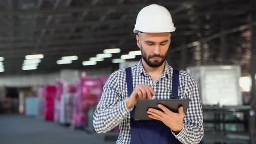 Professioneller Ingenieur der Schwerindustrie, der Sicherheitsuniform und Schutzhelm trägt, verwendet ein Tablet
