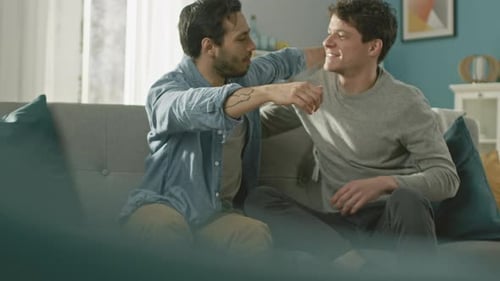 Affectionate Men Sitting on Couch Embrace in Living Room