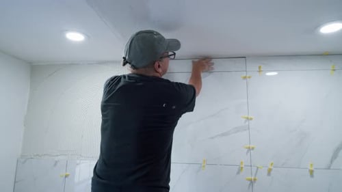 Man Installing Marble Tiles on a Wall Indoors