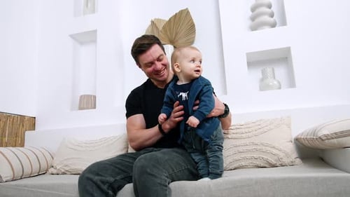 Loving Father Holding Baby Son on Couch