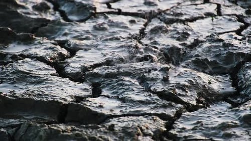 Rain after long drought falls on dry cracked desert ground, climate change