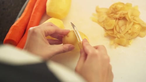 Female hands peeling potatoes in the kitchen in slow motion