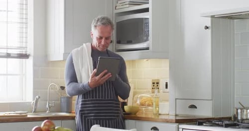 Man Reads Recipe on Tablet in Bright Kitchen