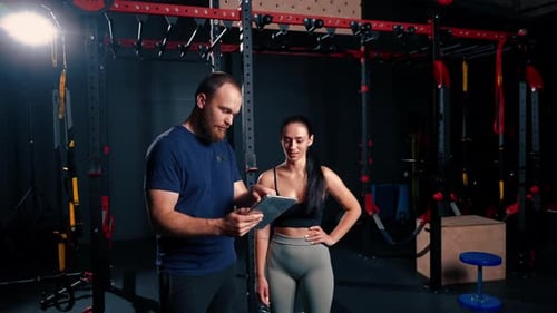 Trainer and Client Looking at Tablet in Gym