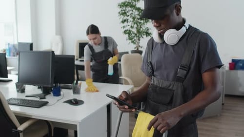 Young Black Cleaner Checking E-mail On Smartphone
