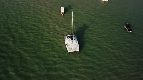 Yacht is Floating in Green Sea Water Next to Little Boats at Warm Summer Day Filmed From Above