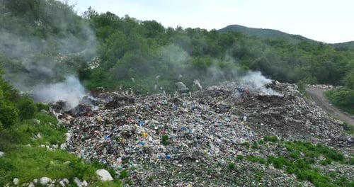 Aerial view of a garbage dump that is burning in places. The landfill is illegally located in the fo