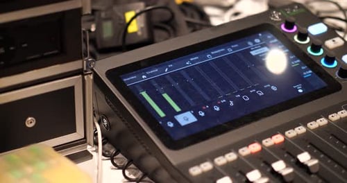 A professional studio with a sound mixing console, knobs, sliders, surrounded by monitors and cables