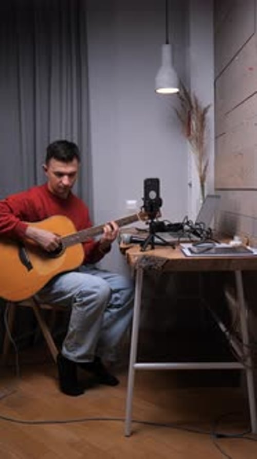 Man Sits and Plays Acoustic Guitar Indoors
