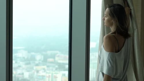Woman Unveil Curtain From Window And Admire View