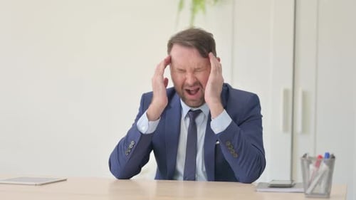 Man in Suit Experiencing a Headache at Desk