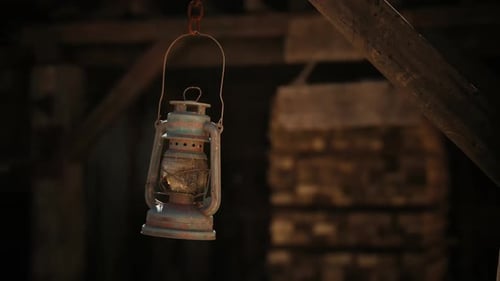 Old Rustic Lantern Swinging in Dark Wooden Barn