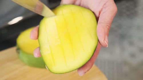 Nahaufnahme von Mango und Mangowürfeln. Das Mädchen schneidet die Mango. Gesundes Essen und Diät