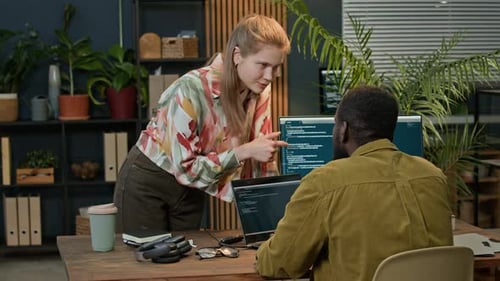 Jeune femme aidant un collègue à développer du Code sur un ordinateur portable