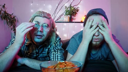 Two Friends Watch TV on a Bed Eating Chips