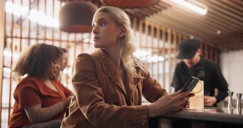 Woman, smartphone and waiting at bar for date, texting and frustrated thinking with cocktail