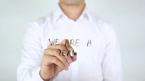 Man Writes 'We Are A Team' on Clear Surface