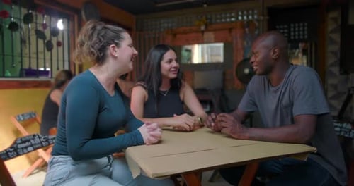 Three friends sitting at café table engaged in lively conversation expressing ease humor trust and