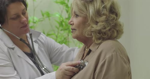 Doctor Examining Mature Woman with Stethoscope in Office